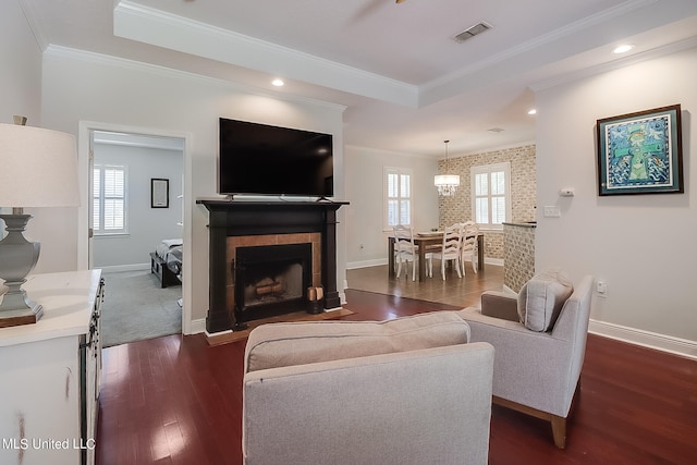 living room featuring crown molding, a notable chandelier, dark hardwood / wood-style flooring, and a fireplace