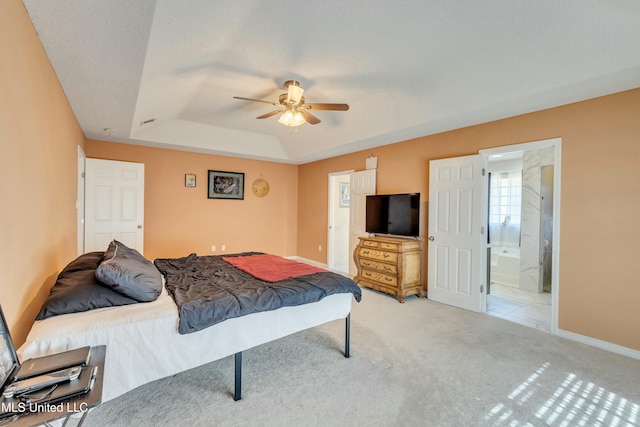 bedroom featuring light carpet, ensuite bathroom, a raised ceiling, and ceiling fan