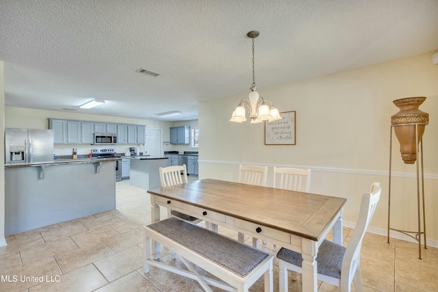 tiled dining space with a chandelier and a textured ceiling