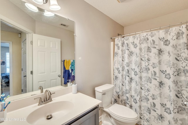 bathroom with a shower with curtain, vanity, a textured ceiling, and toilet