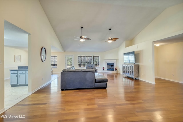 living room featuring ceiling fan, high vaulted ceiling, and light hardwood / wood-style floors