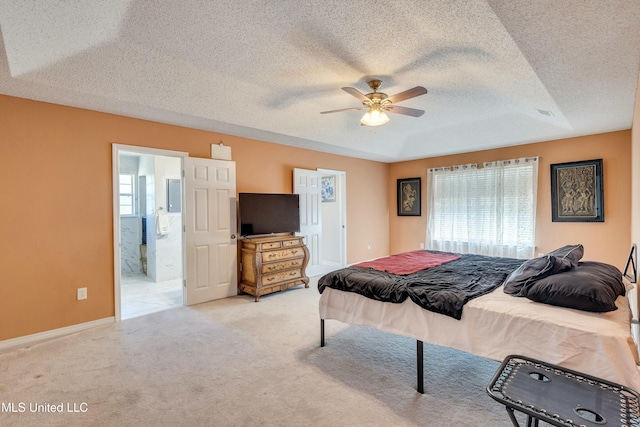 carpeted bedroom featuring a textured ceiling, connected bathroom, a raised ceiling, and ceiling fan