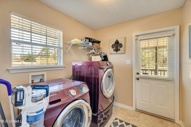 clothes washing area featuring washing machine and clothes dryer, light tile patterned floors, and a textured ceiling