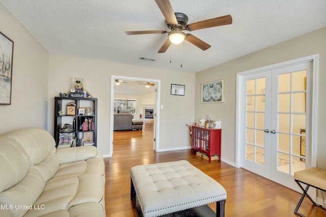 living room featuring french doors, a textured ceiling, and hardwood / wood-style flooring