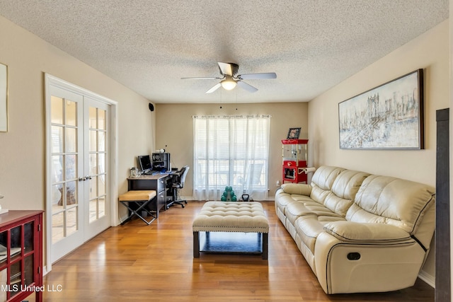 living room featuring hardwood / wood-style flooring, ceiling fan, a textured ceiling, and french doors