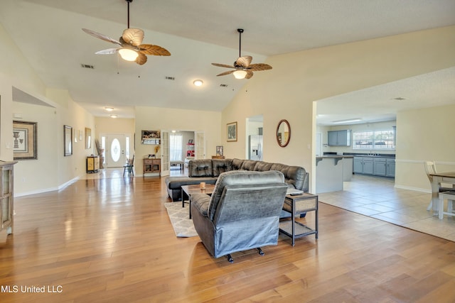 living room featuring light hardwood / wood-style flooring, high vaulted ceiling, and ceiling fan