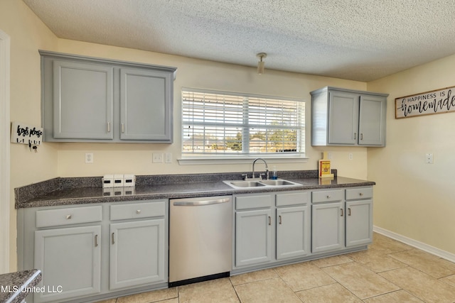 kitchen featuring gray cabinetry, sink, stainless steel dishwasher, and a textured ceiling