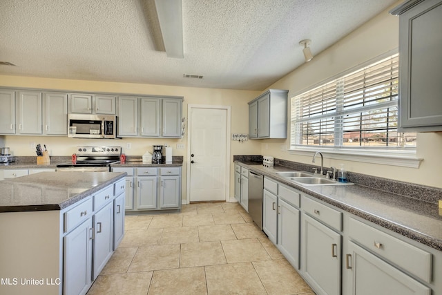 kitchen featuring gray cabinetry, sink, light tile patterned floors, a textured ceiling, and appliances with stainless steel finishes