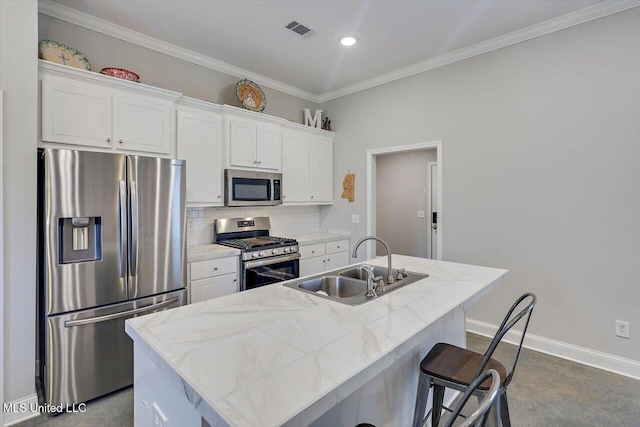 946 Filmore Dr, Brandon, MS 39042 - kitchen featuring appliances with stainless steel finishes, an island with sink, white cabinetry, crown molding, and backsplash