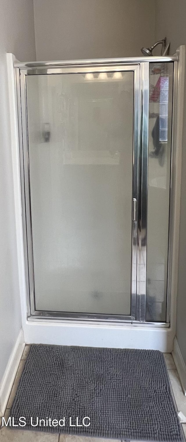 bathroom with a shower with shower door and tile patterned flooring