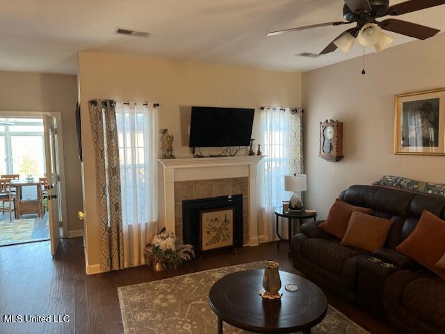 living room with a fireplace, dark wood-type flooring, and ceiling fan