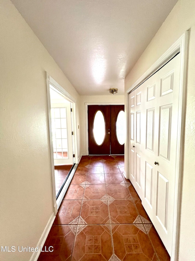 doorway with a baseboard heating unit and dark tile patterned flooring