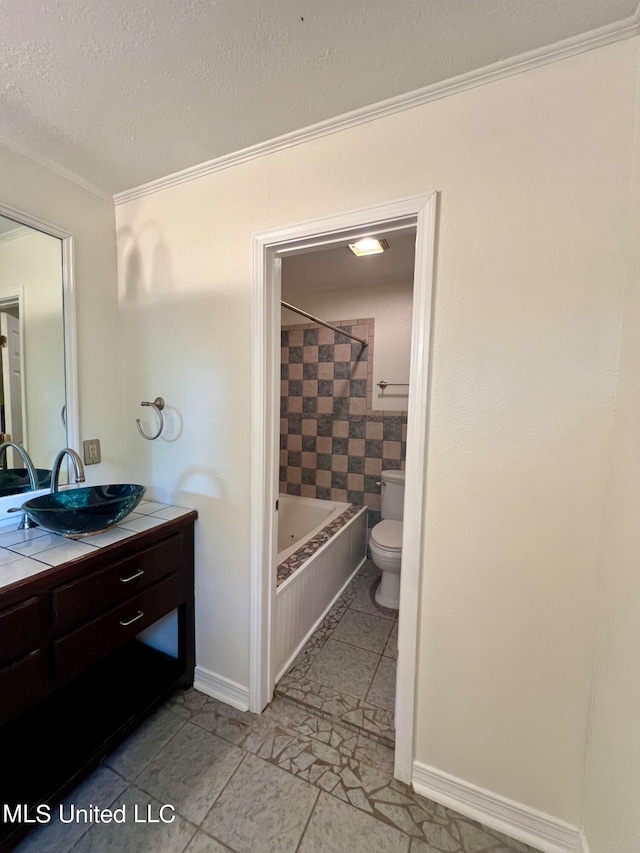 full bathroom with tiled shower / bath, toilet, ornamental molding, vanity, and tile patterned floors