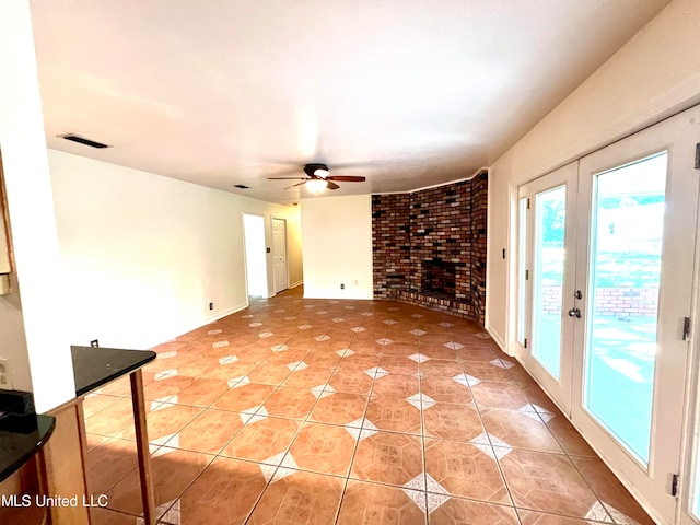 unfurnished living room with french doors, ceiling fan, brick wall, and light tile patterned floors