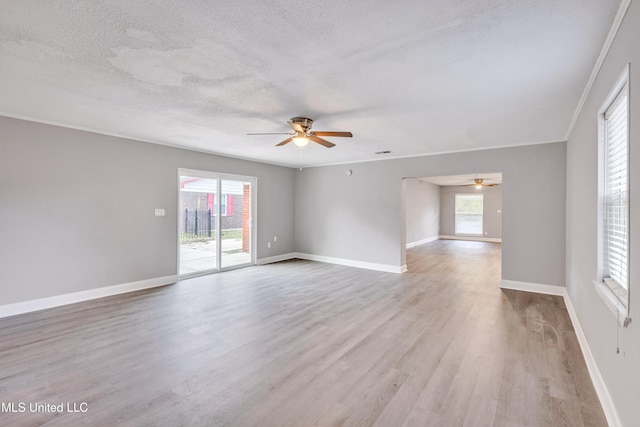 empty room featuring ceiling fan, a wealth of natural light, a textured ceiling, and light hardwood / wood-style flooring