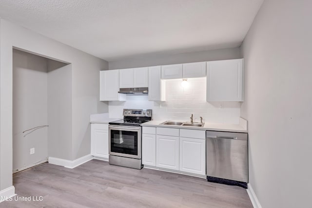 kitchen featuring stainless steel appliances, white cabinetry, sink, and light hardwood / wood-style floors