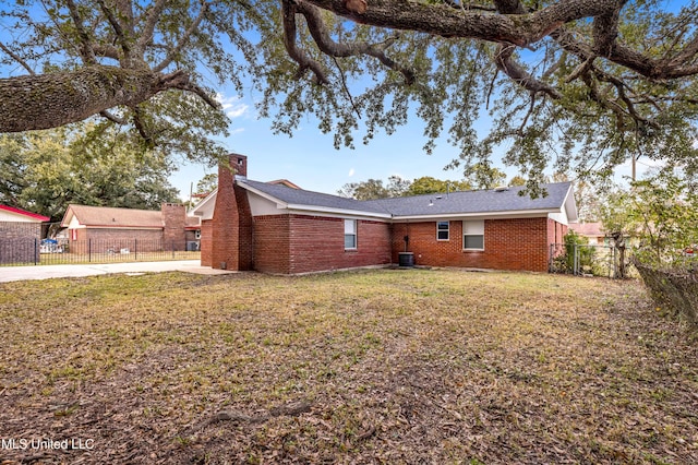 rear view of property with central AC unit and a yard