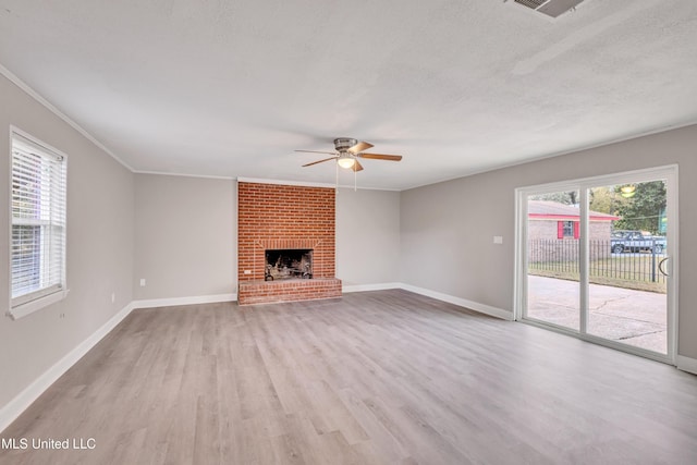 unfurnished living room featuring ceiling fan, plenty of natural light, light hardwood / wood-style floors, and a brick fireplace