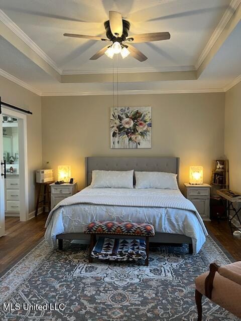 bedroom featuring a tray ceiling, a barn door, wood finished floors, and crown molding