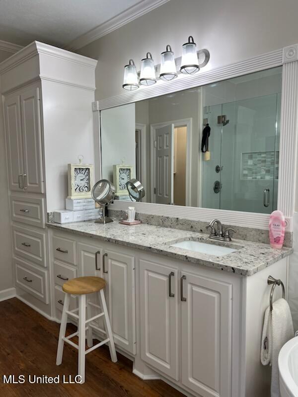 bathroom with ornamental molding, a stall shower, vanity, and wood finished floors