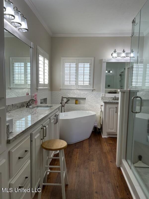 full bath with wood finished floors, tile walls, a freestanding bath, a stall shower, and crown molding