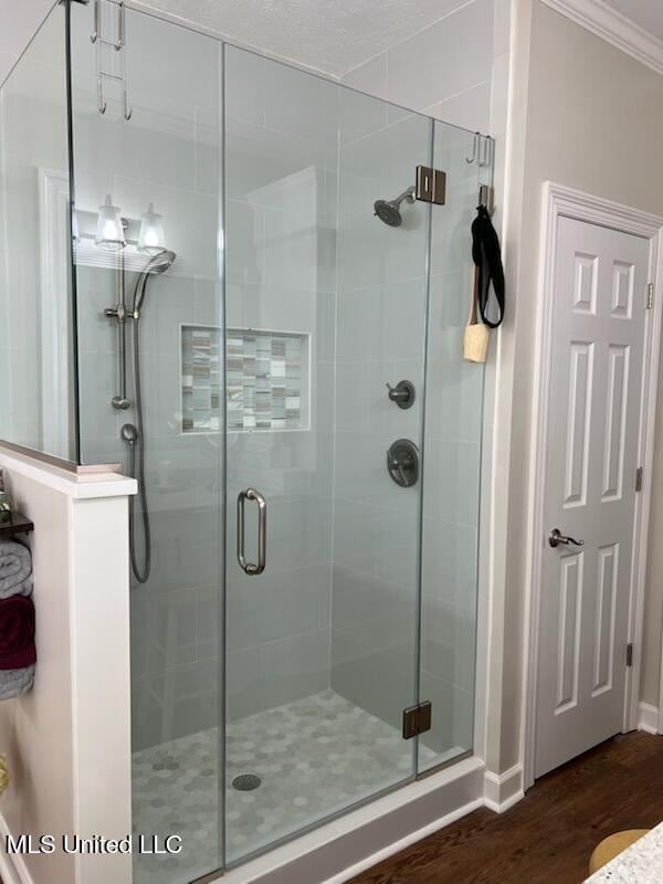 full bathroom featuring a shower stall, crown molding, and wood finished floors