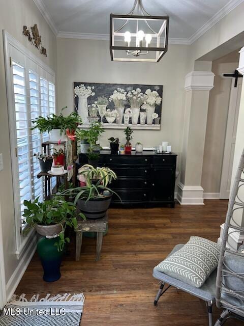 living area with an inviting chandelier, baseboards, ornamental molding, and wood finished floors