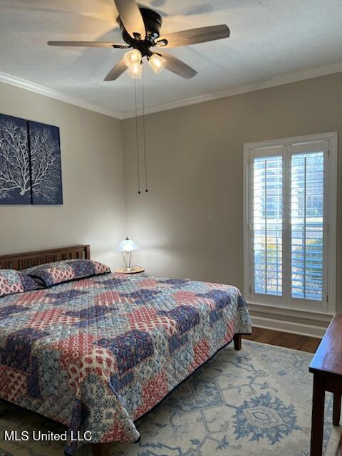 bedroom featuring ceiling fan, ornamental molding, and wood finished floors