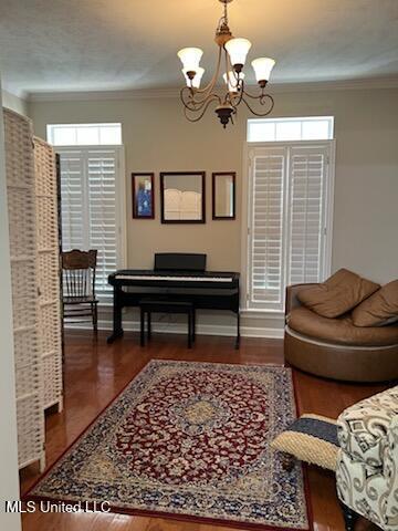 sitting room featuring ornamental molding, wood finished floors, a wealth of natural light, and a notable chandelier