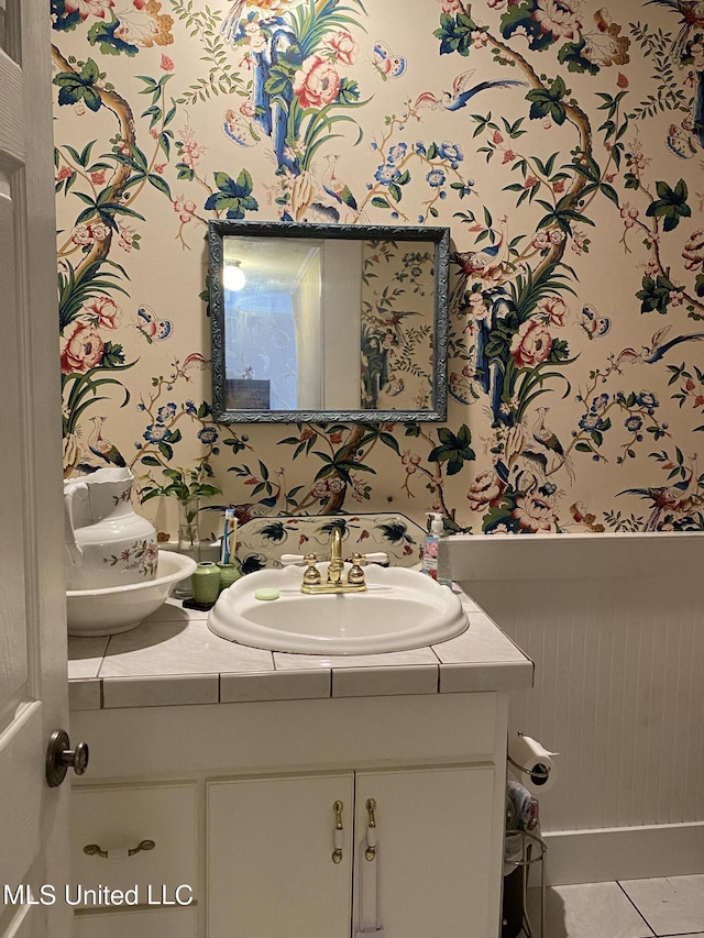 half bath featuring tile patterned floors, wallpapered walls, and vanity