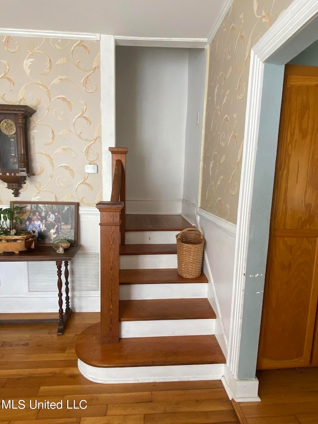 stairway with ornamental molding and hardwood / wood-style flooring