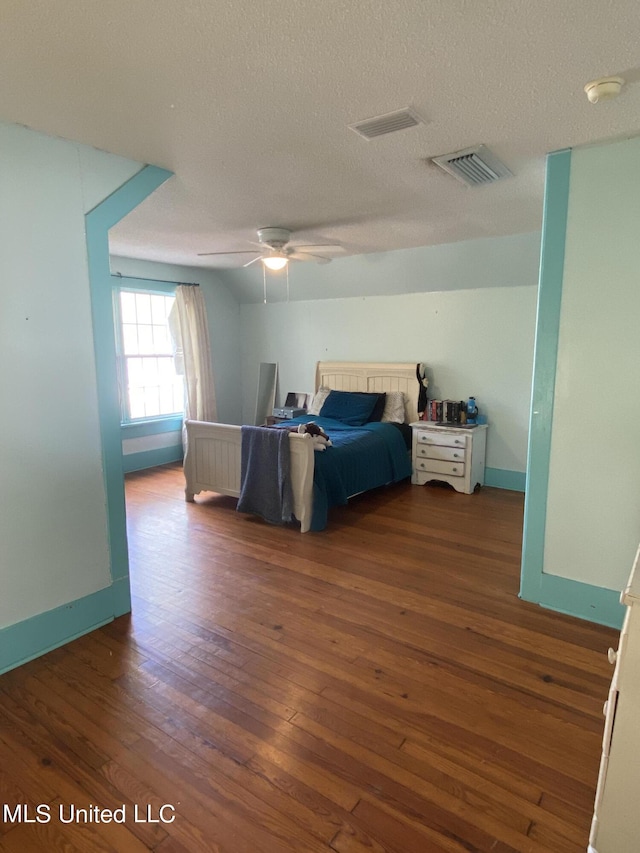 bedroom with baseboards, visible vents, wood finished floors, and a textured ceiling