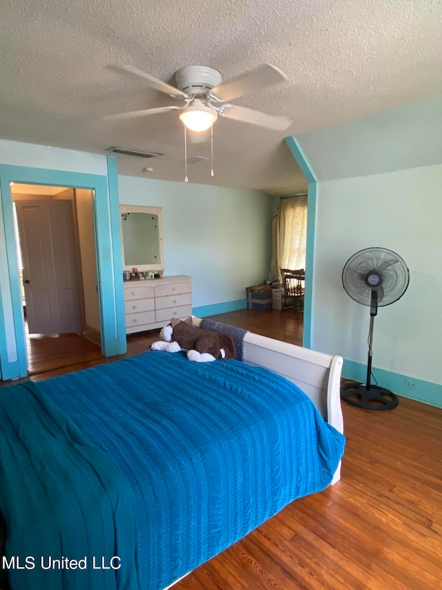 bedroom featuring hardwood / wood-style floors, a textured ceiling, and ceiling fan