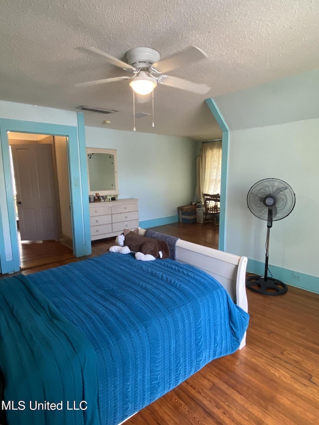 bedroom featuring a textured ceiling, visible vents, wood finished floors, and a ceiling fan