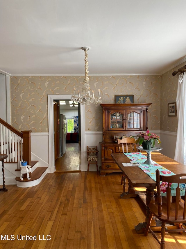 dining area with crown molding, hardwood / wood-style flooring, and a chandelier