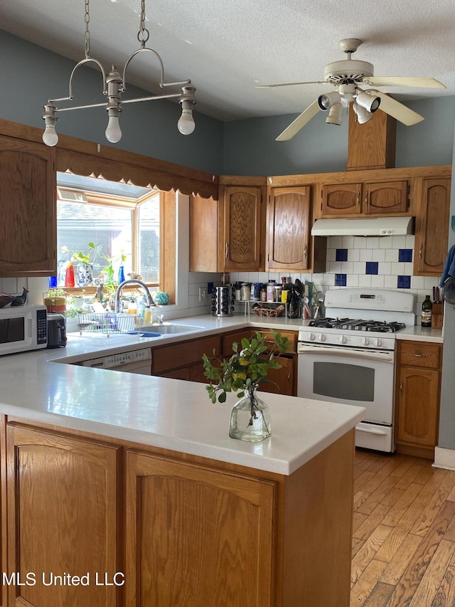 kitchen with white appliances, light countertops, and under cabinet range hood