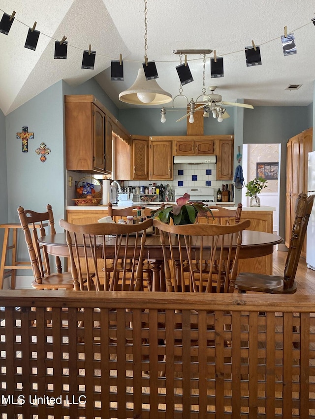 dining room featuring visible vents, ceiling fan, a textured ceiling, and vaulted ceiling
