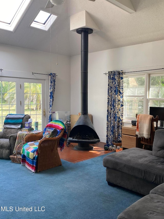 living room featuring carpet, a wood stove, a textured ceiling, and lofted ceiling with skylight