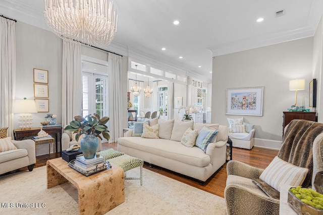 living room featuring crown molding, wood-type flooring, and an inviting chandelier