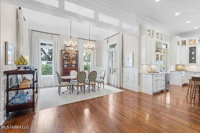 dining area featuring wine cooler, hardwood / wood-style floors, a notable chandelier, and crown molding