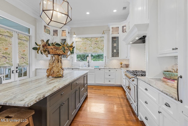 kitchen with a kitchen breakfast bar, white cabinetry, light hardwood / wood-style floors, decorative light fixtures, and decorative backsplash