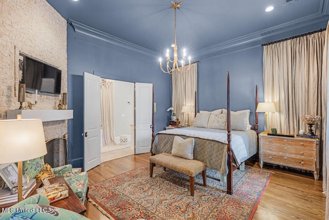 bedroom with a large fireplace, crown molding, a notable chandelier, and light wood-type flooring