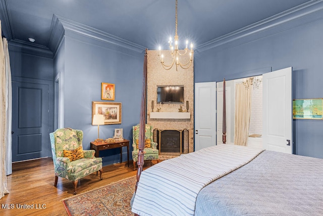 bedroom with crown molding, hardwood / wood-style floors, a notable chandelier, and a fireplace