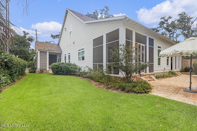 rear view of property featuring a patio area, a yard, and a sunroom