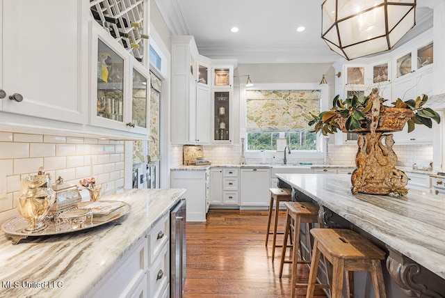 kitchen featuring hanging light fixtures, white cabinetry, light stone counters, and ornamental molding