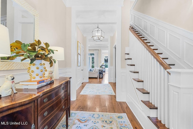 entryway with a notable chandelier, ornamental molding, and light wood-type flooring