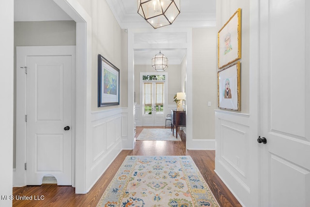 entryway featuring ornamental molding, wood-type flooring, and an inviting chandelier