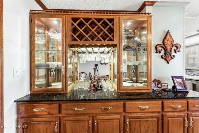 bar with a textured ceiling, visible vents, indoor bar, and crown molding