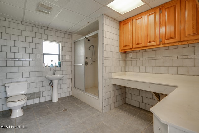 bathroom featuring toilet, a drop ceiling, tile patterned flooring, and an enclosed shower