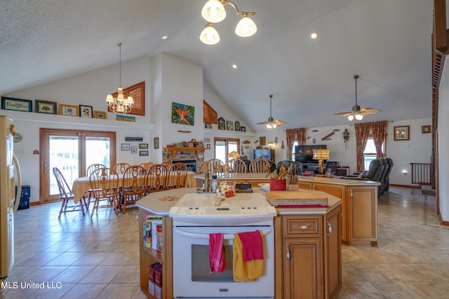 kitchen featuring a center island with sink, light tile patterned floors, a textured ceiling, high vaulted ceiling, and ceiling fan with notable chandelier